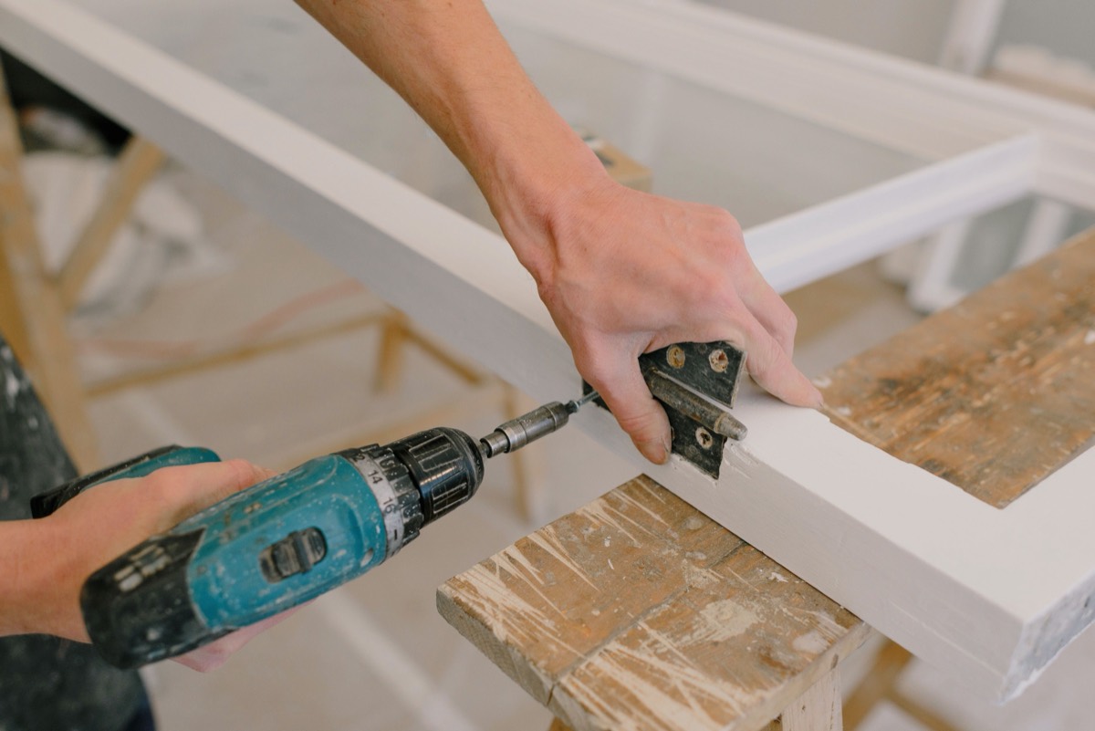 Artisan menuisier fixant une pièce de bois à la perceuse